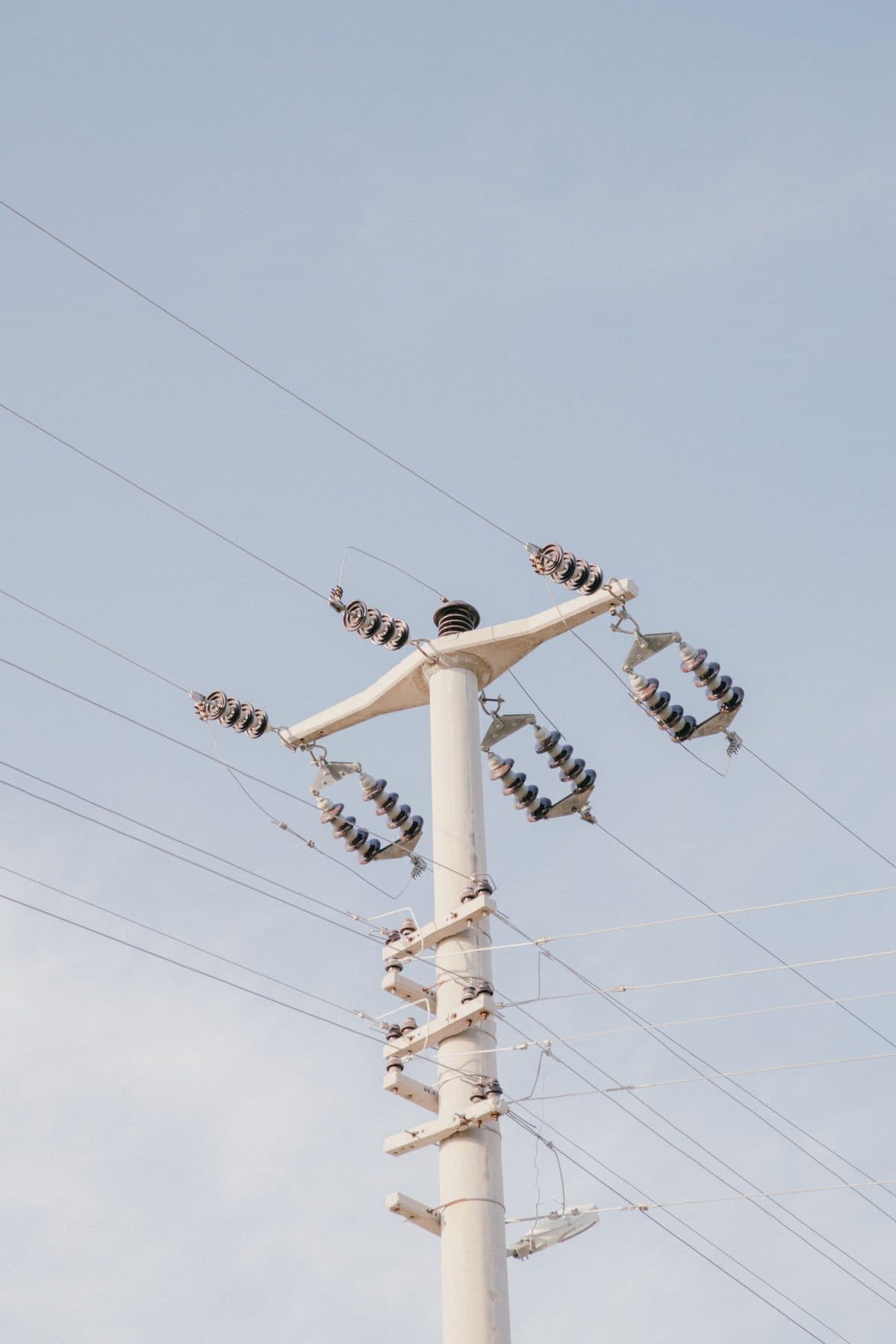 Gökyüzü önünde izolatörlü elektrik dağıtım direği